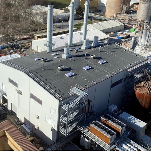 Zu sehen ist das Gebäude des Kraftwerks mit drei Türmen, dahinter das alte Kohlekraftwerk.