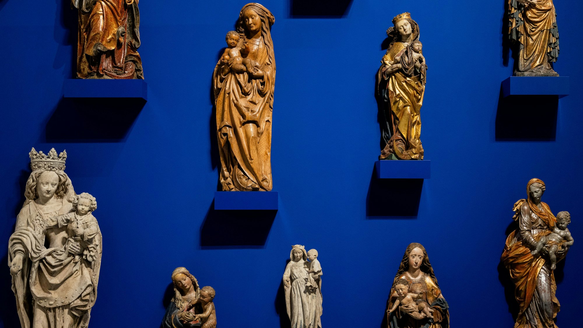 PRODUKTION - 10.03.2025, Nordrhein-Westfalen, Düsseldorf: Muttergottesfiguren sind in der Ausstellung ·Mama. Von Maria bis Merkel· im Museum Kunstpalast zu sehen. Foto: Rolf Vennenbernd/dpa - ACHTUNG: Nur zur redaktionellen Verwendung im Zusammenhang mit der aktuellen Berichterstattung über die genannte Ausstellung und nur mit vollständiger Nennung des vorstehenden Credits +++ dpa-Bildfunk +++
