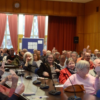 Ein Blick in den Saal mit Frauen und Männern, die in Reihen sitzen.