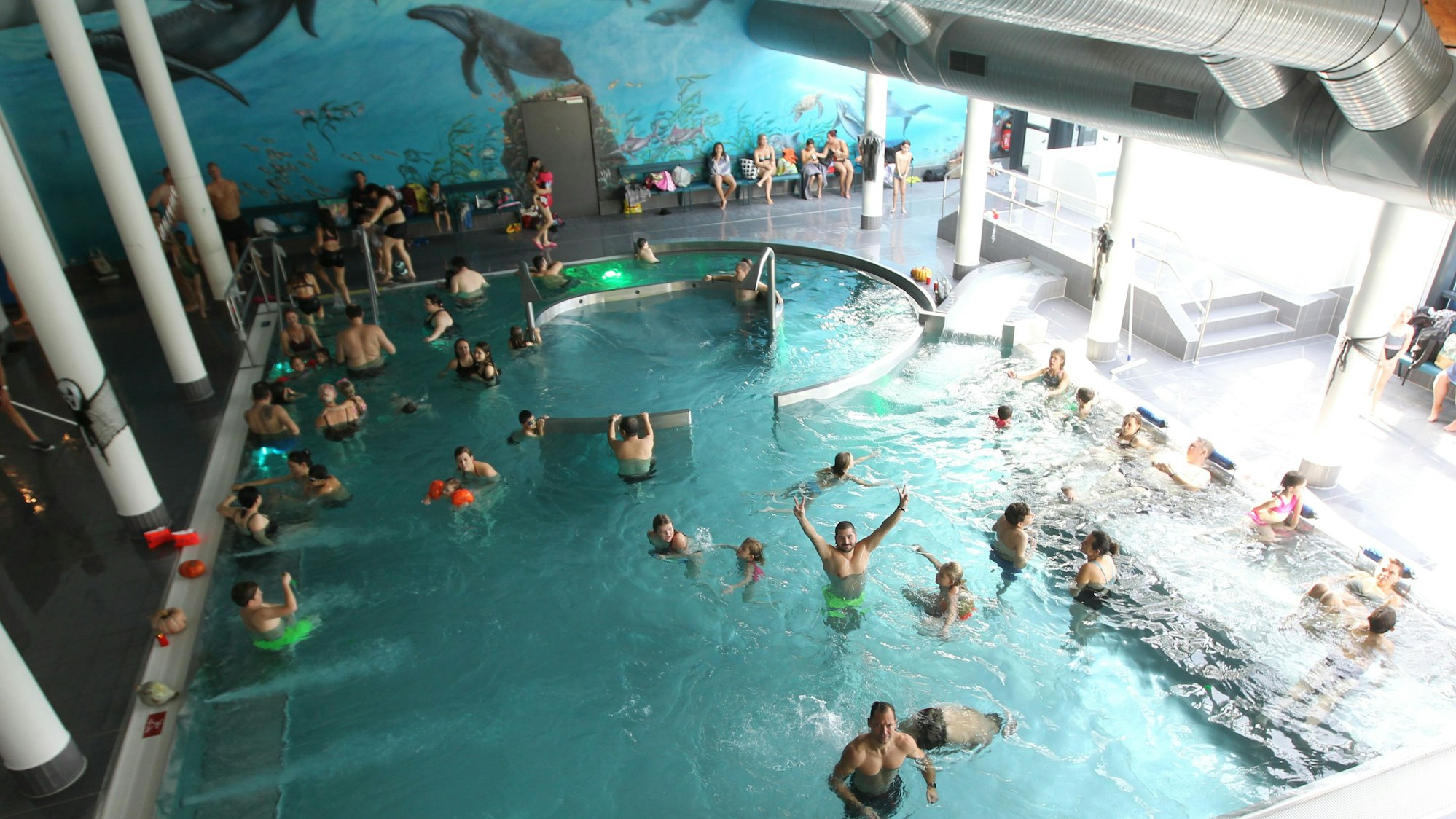 Menschen im Becken eines Hallenbades.