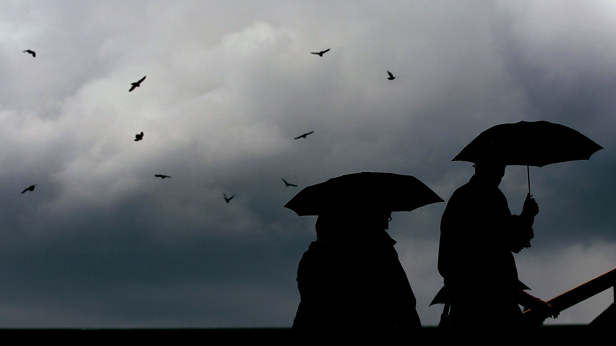 Passanten gehen mit Regenschirmen durch eine Stadt.
