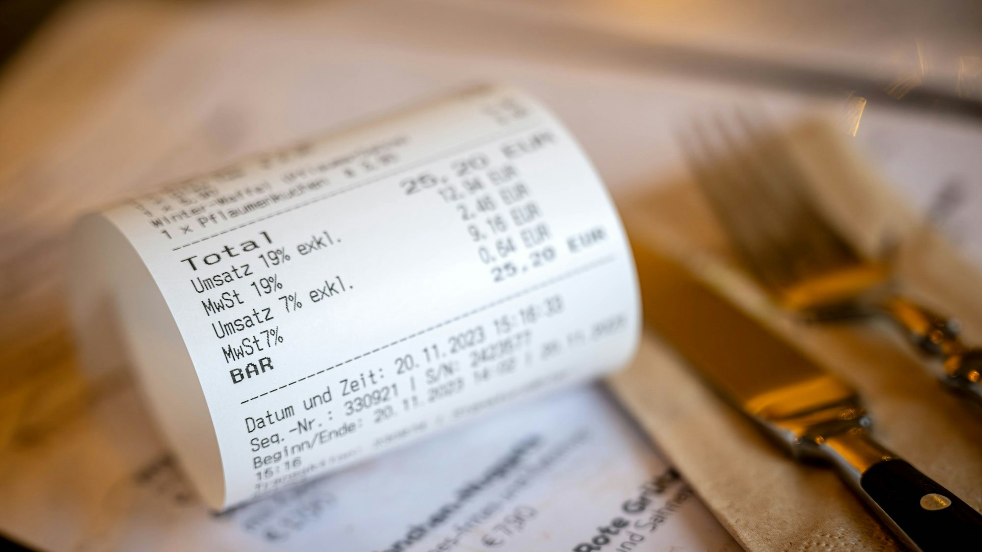 Eine Rechnung mit Umsatzsteuer und Mehrwertsteuer liegt auf der Speisekarte eines Restaurants.