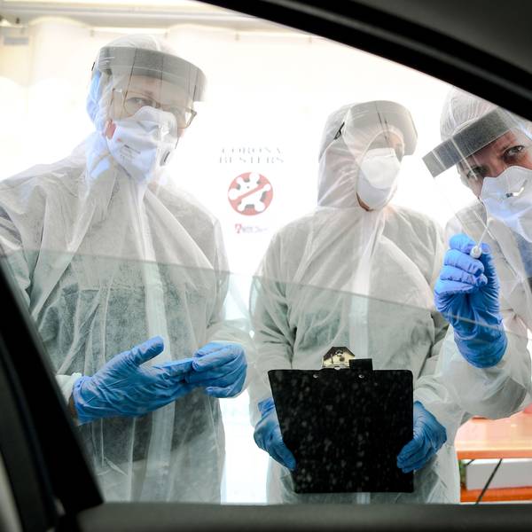 Mitarbeiter vom Gesundheitsamt halten ein Abstrichstäbchen in ein Autofenster in der ambulanten Corona-Test- Einrichtung. (Archivbild)