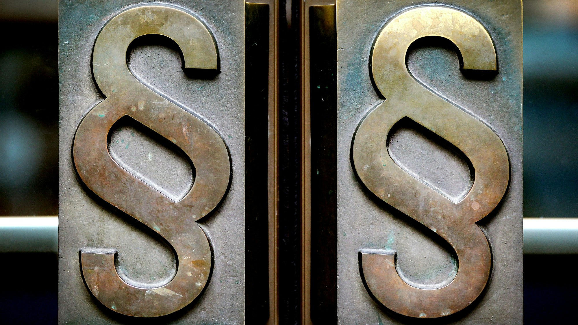 Paragrafen-Symbole sind an Türgriffen am Eingang zum Landgericht Bonn angebracht.