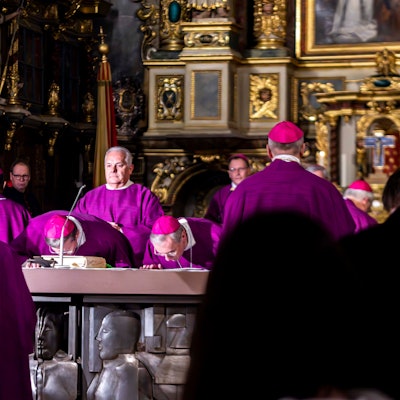Viele Bischöfe in lila Gewändern stehen um einen Altar.