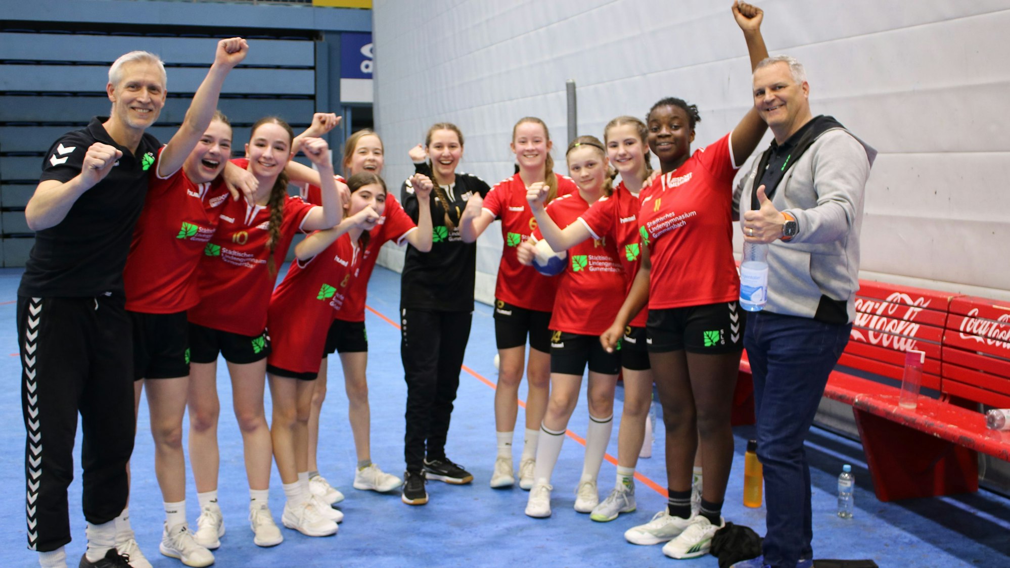 Die Handballerinnen des Lindengymnasiums stehen die Fäuste gereckt mit ihren Trainern im Halbrund.