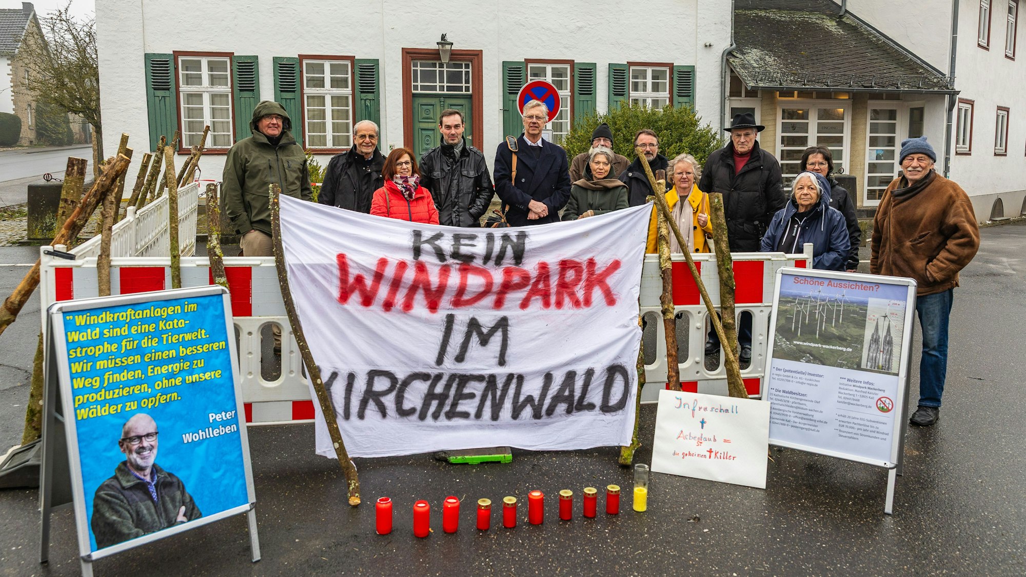 Eine 13-köpfige Gruppe hat sich mit dem Transparent „Kein Windpark im Kirchenwald“ und Plakaten am Eingang zum Kloster postiert.