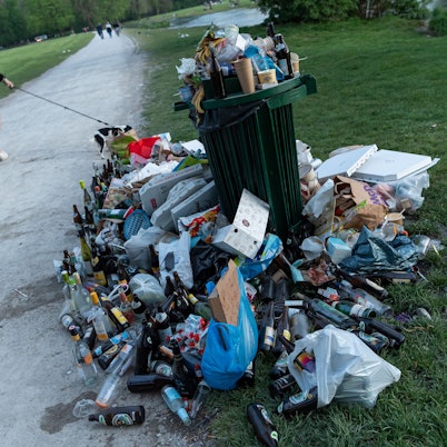 Ein zugemüllter Abfallbehälter in einem Park.
