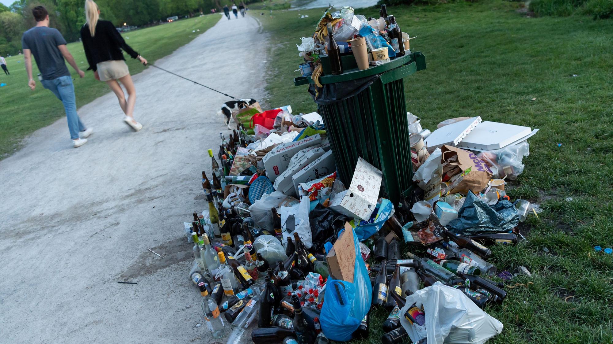 Ein zugemüllter Abfallbehälter in einem Park.