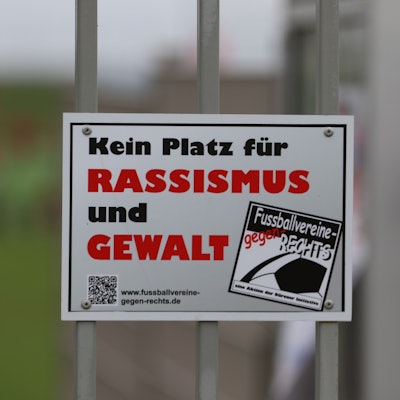 Auf einem Schild an einem Sportplatzzaun steht „Kein Platz für Rassismus und Gewalt“.