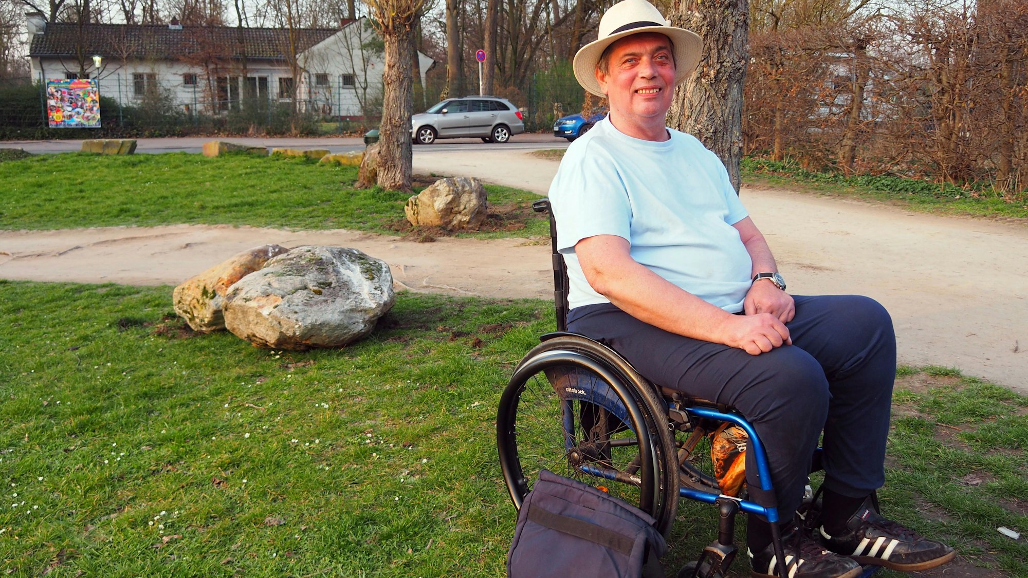 Ein Mann sitzt in einem Rollstuhl in einem Park.