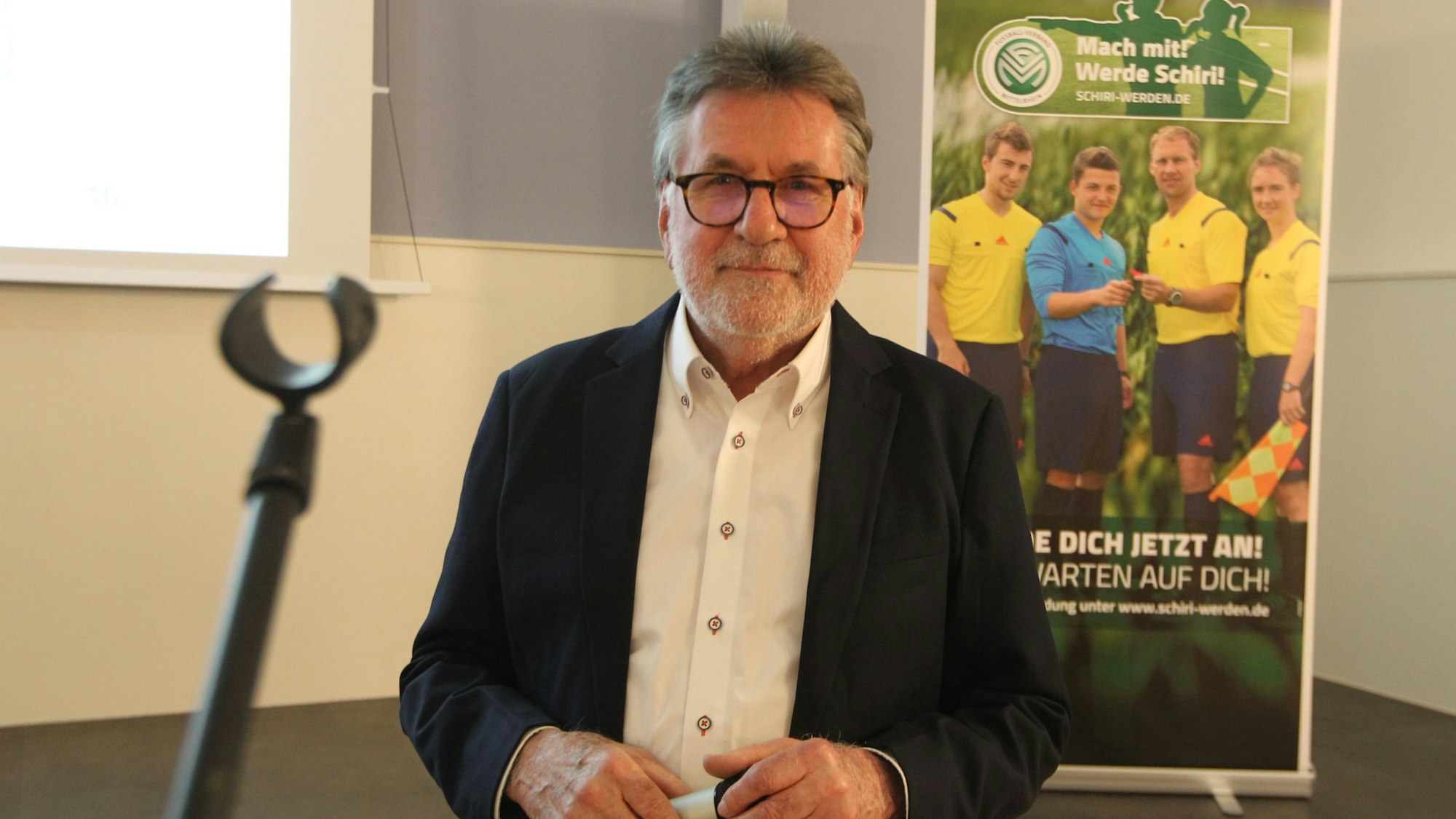 Ein Mann mit Brille im Sakko und weißen Hemd.