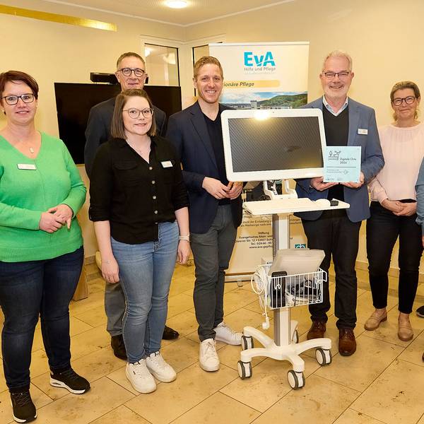 Drei Frauen und fünf Männer stehen um einen fahrbaren Computer, der im Altenheim in Gemünd im Bereich der Telemedizin eingesetzt wird.