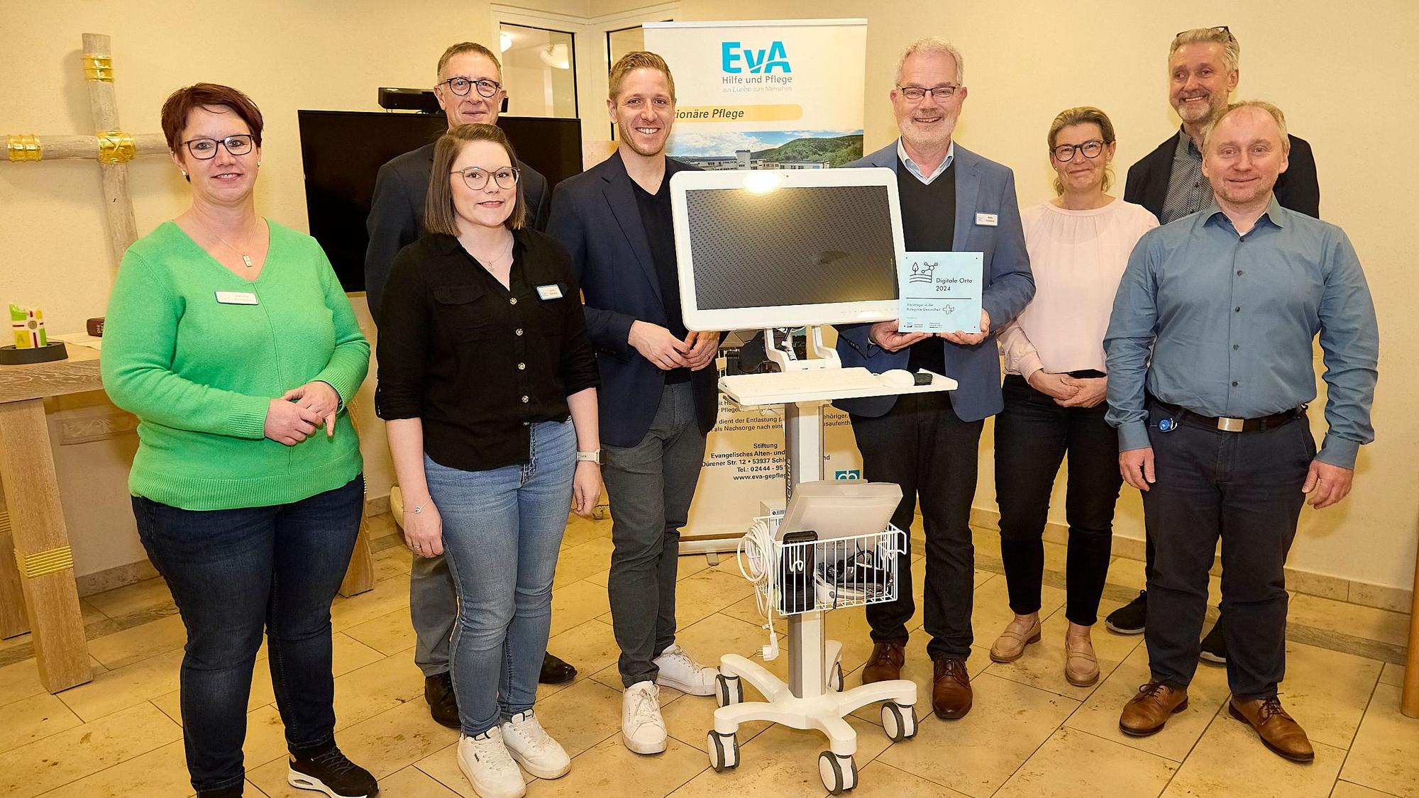 Drei Frauen und fünf Männer stehen um einen fahrbaren Computer, der im Altenheim in Gemünd im Bereich der Telemedizin eingesetzt wird.