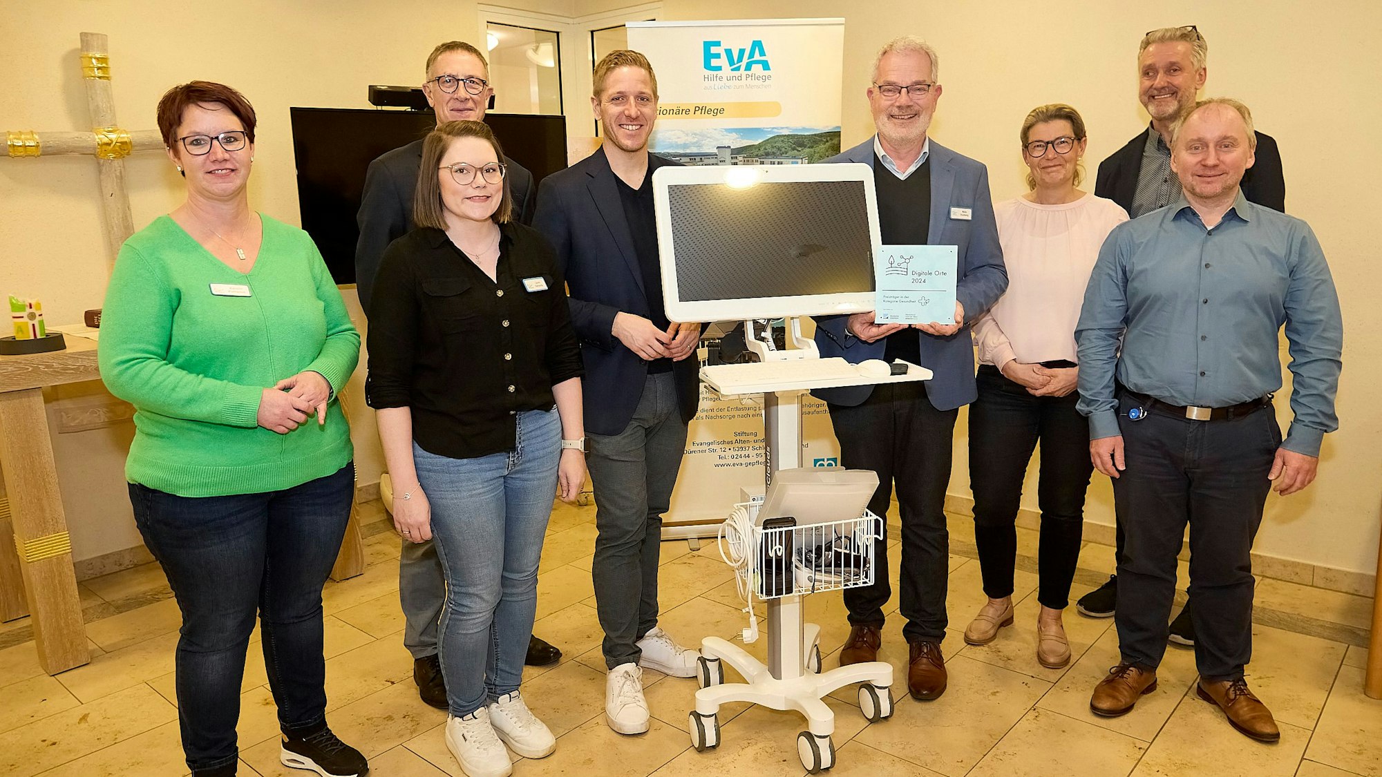 Drei Frauen und fünf Männer stehen um einen fahrbaren Computer, der im Altenheim in Gemünd im Bereich der Telemedizin eingesetzt wird.