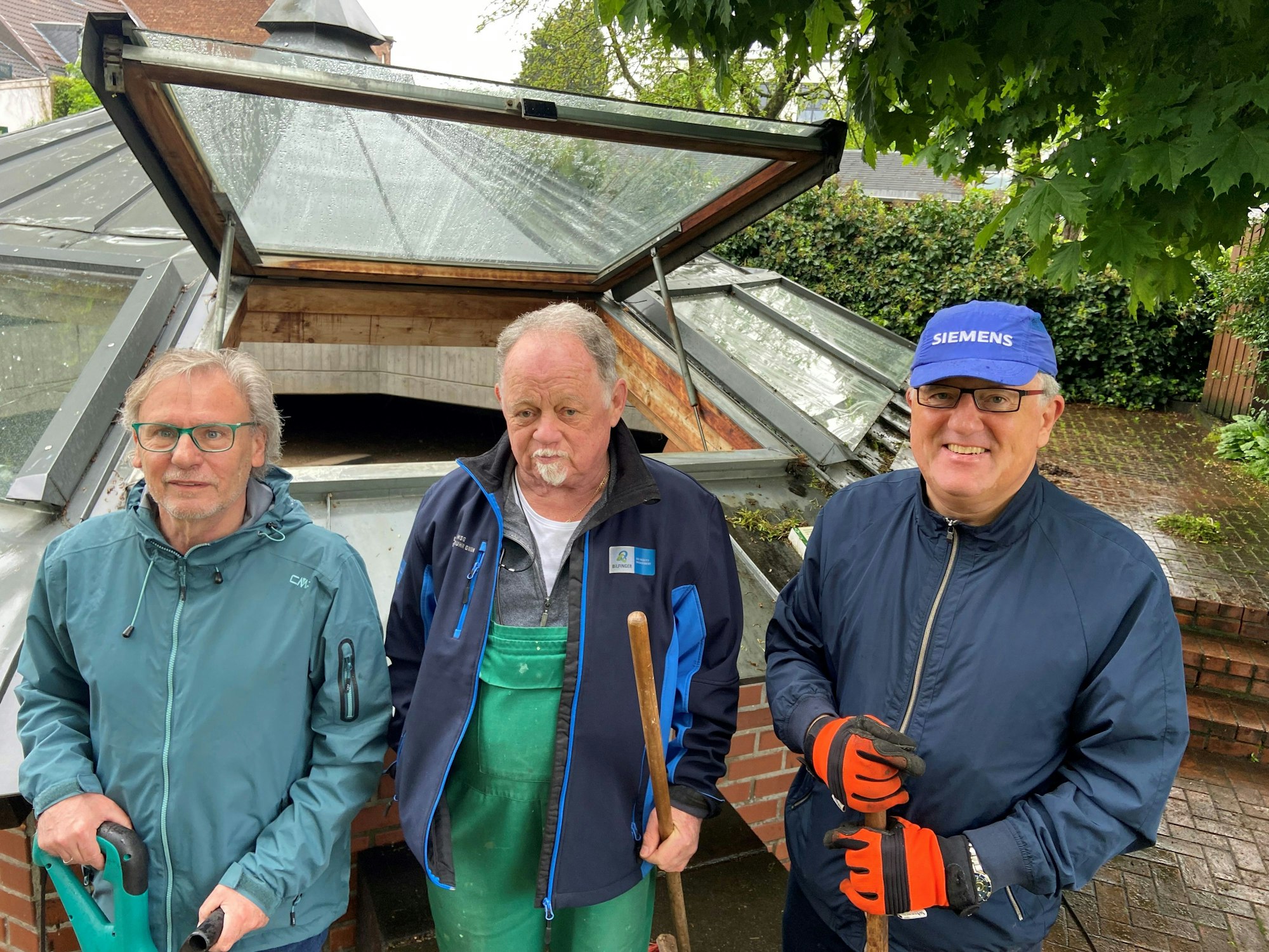 Auf dem Bild sind drei Männer mit Werkzeug zu sehen, die sich um einen Töpferofen kümmern.