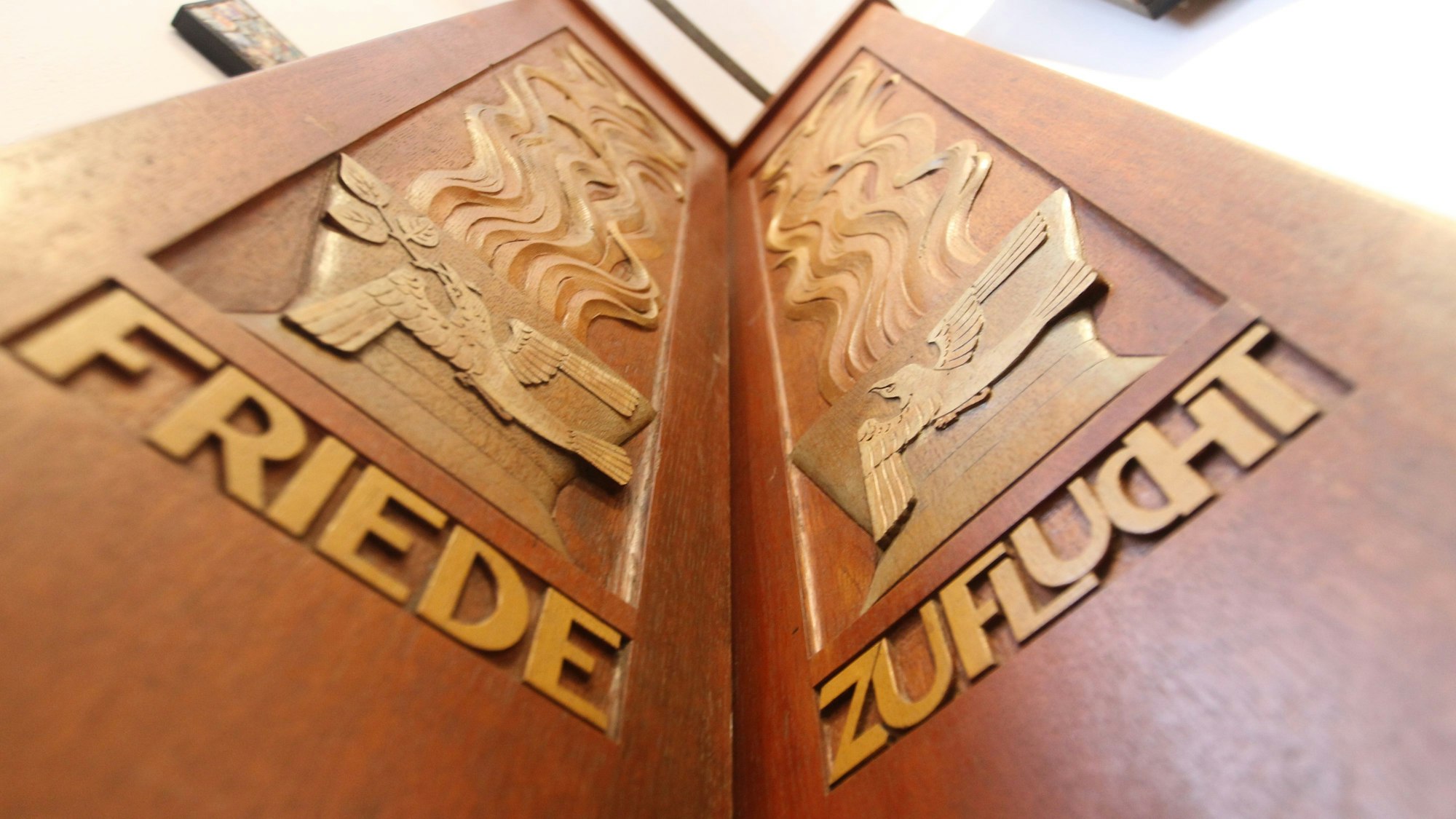 Zwei Holzbretter, eingeschnitzt sind die Wörter Friede und Zuflucht.