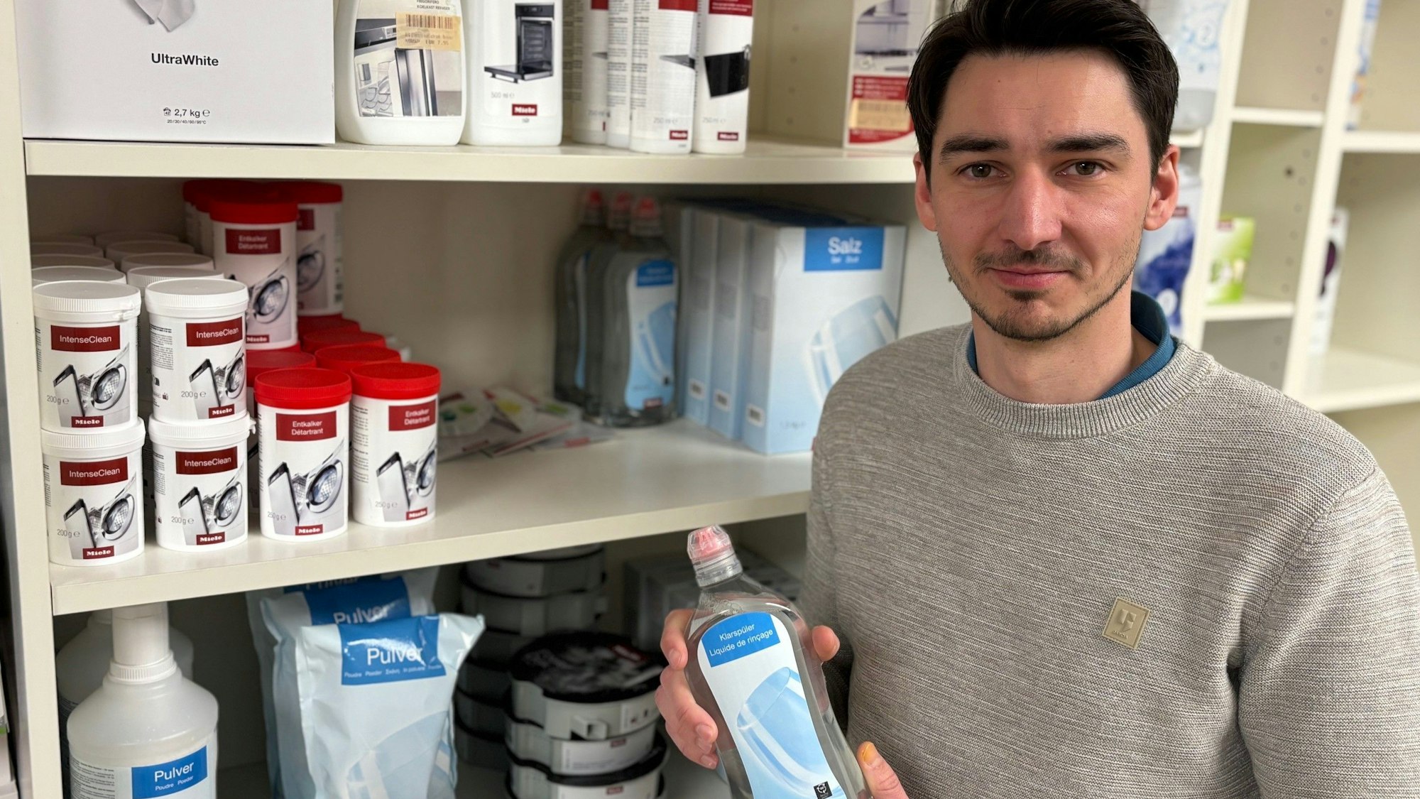 Auf dem Bild ist ein Mann zu sehen, der ein Pflegeprodukt für Spülmaschinen hält.
