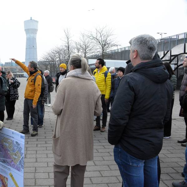 Eine Gruppe von Menschen diskutiert vor einem Wasserturm.