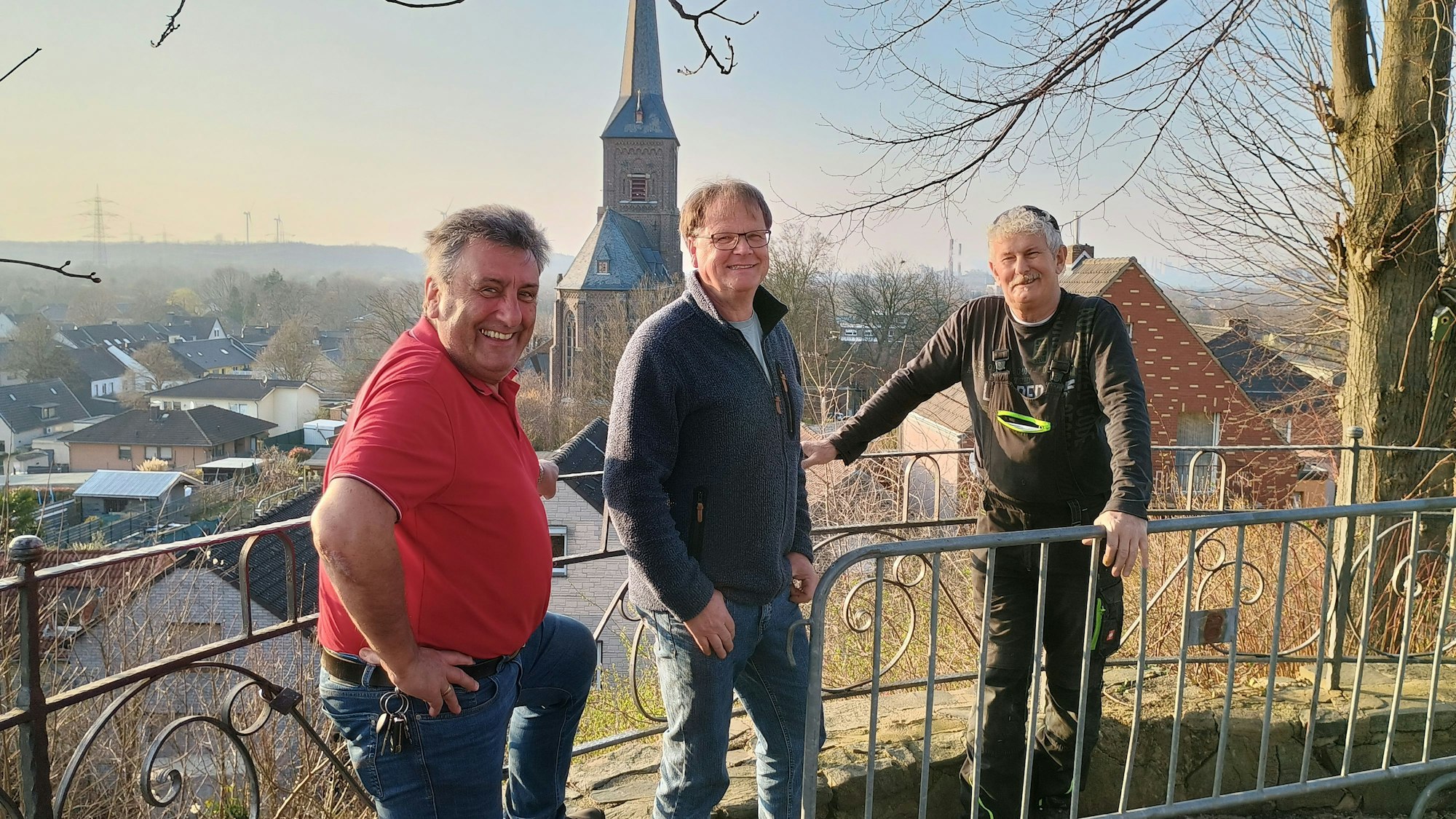 Drei Männer stehen vor einem Geländer unter dem Baum, dahinter die Aussicht auf Oberaußem.