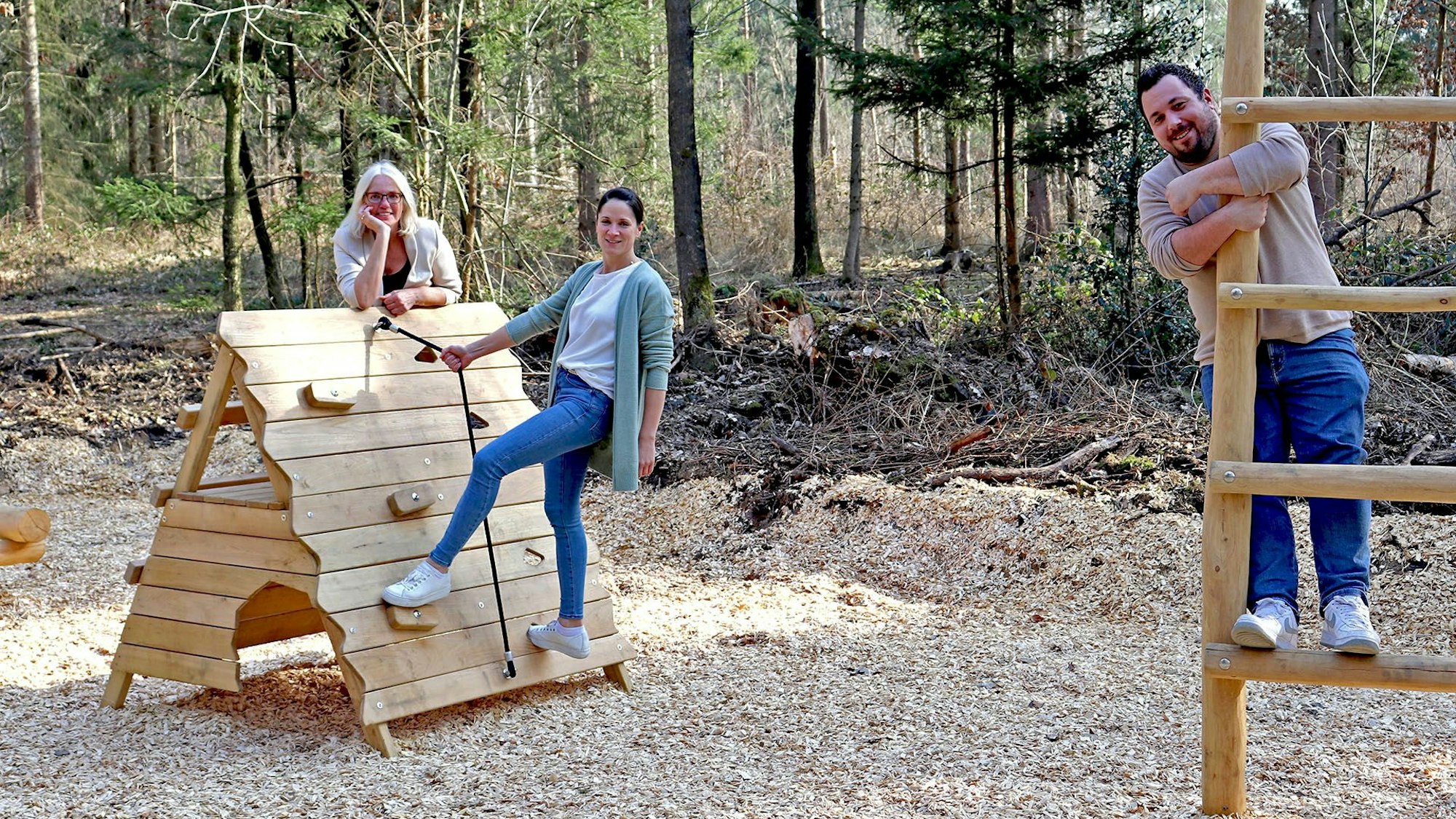 Zwei Frauen und ein Mann auf Klettergeräten im Wald