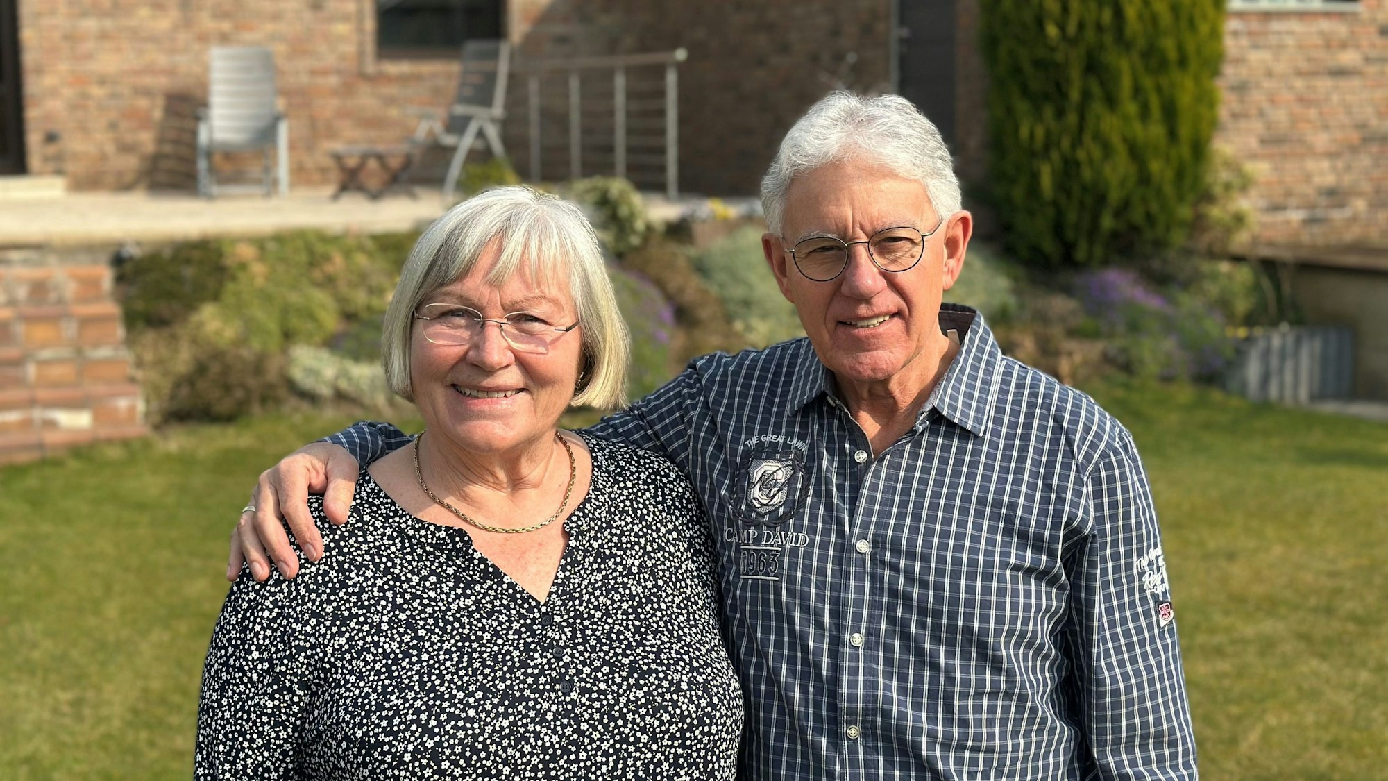 Ein Ehepaar steht in seinem Garten.