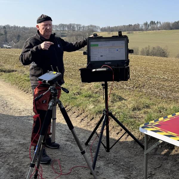 Ein Mann startet auf einem Feld eine Drohne.