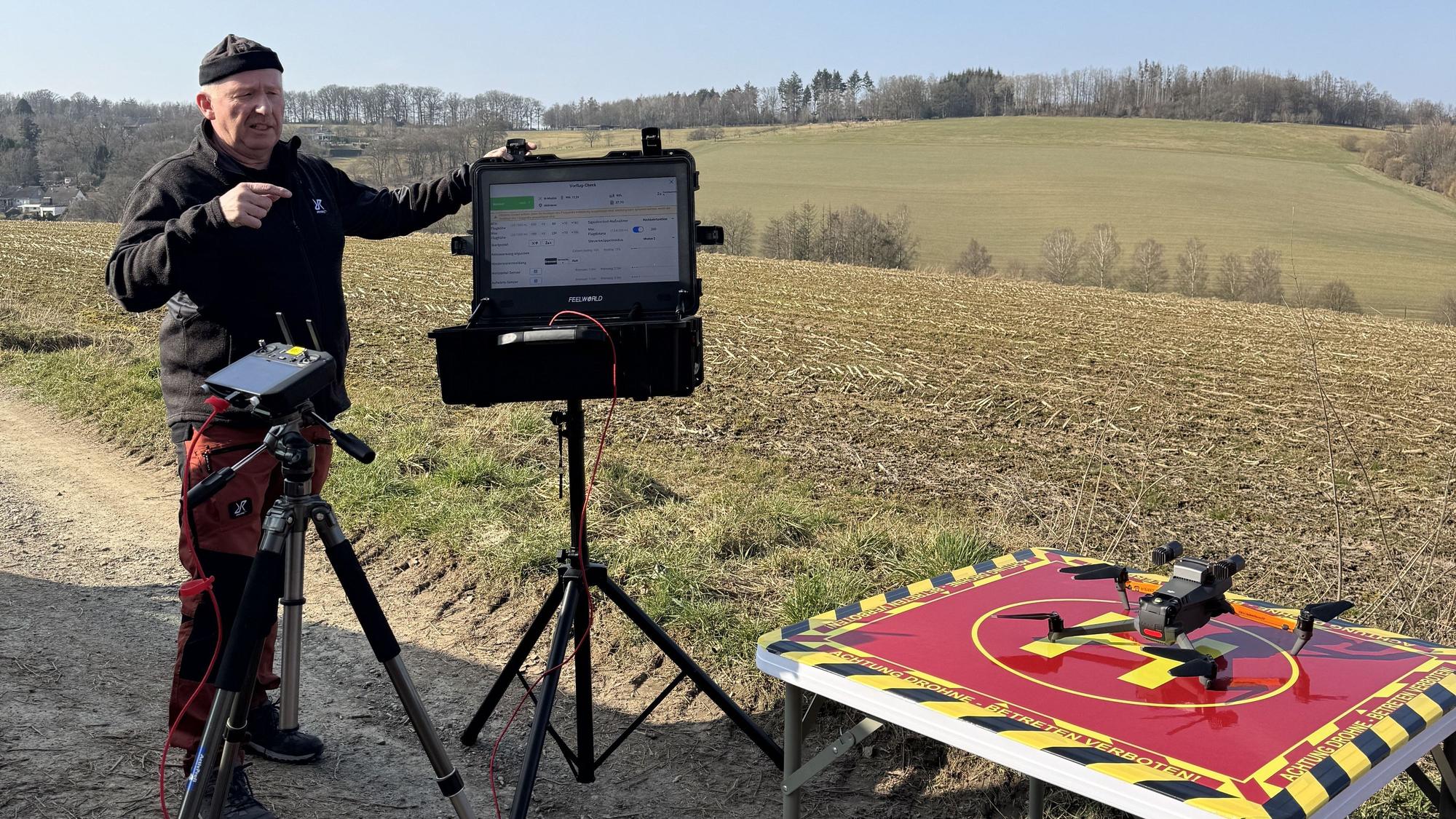 Ein Mann startet auf einem Feld eine Drohne.