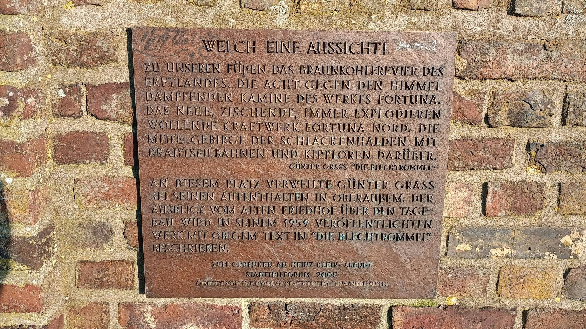 Die Bronzene Tafel ist mit „Welche eine Aussicht!“ überschrieben und beschreibt, wie Grass auf das Braunkohlerevier des Erftlandes schaut.