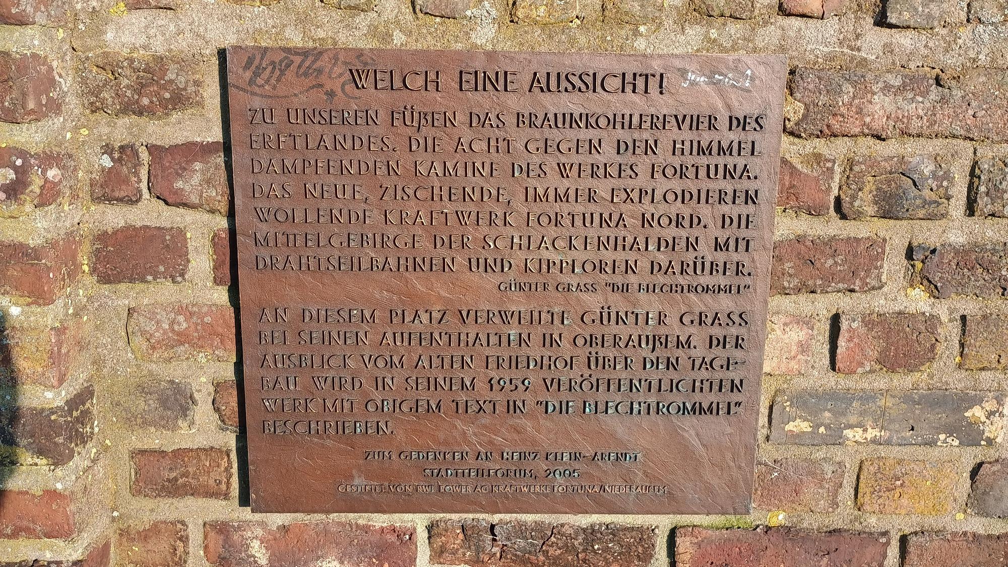 Die Bronzene Tafel ist mit „Welche eine Aussicht!“ überschrieben und beschreibt, wie Grass auf das Braunkohlerevier des Erftlandes schaut.