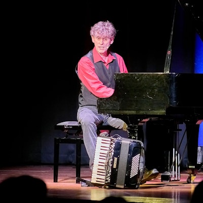 Axel Pätz sitzt am Flügel, auf dem Boden steht ein Akkordeon.