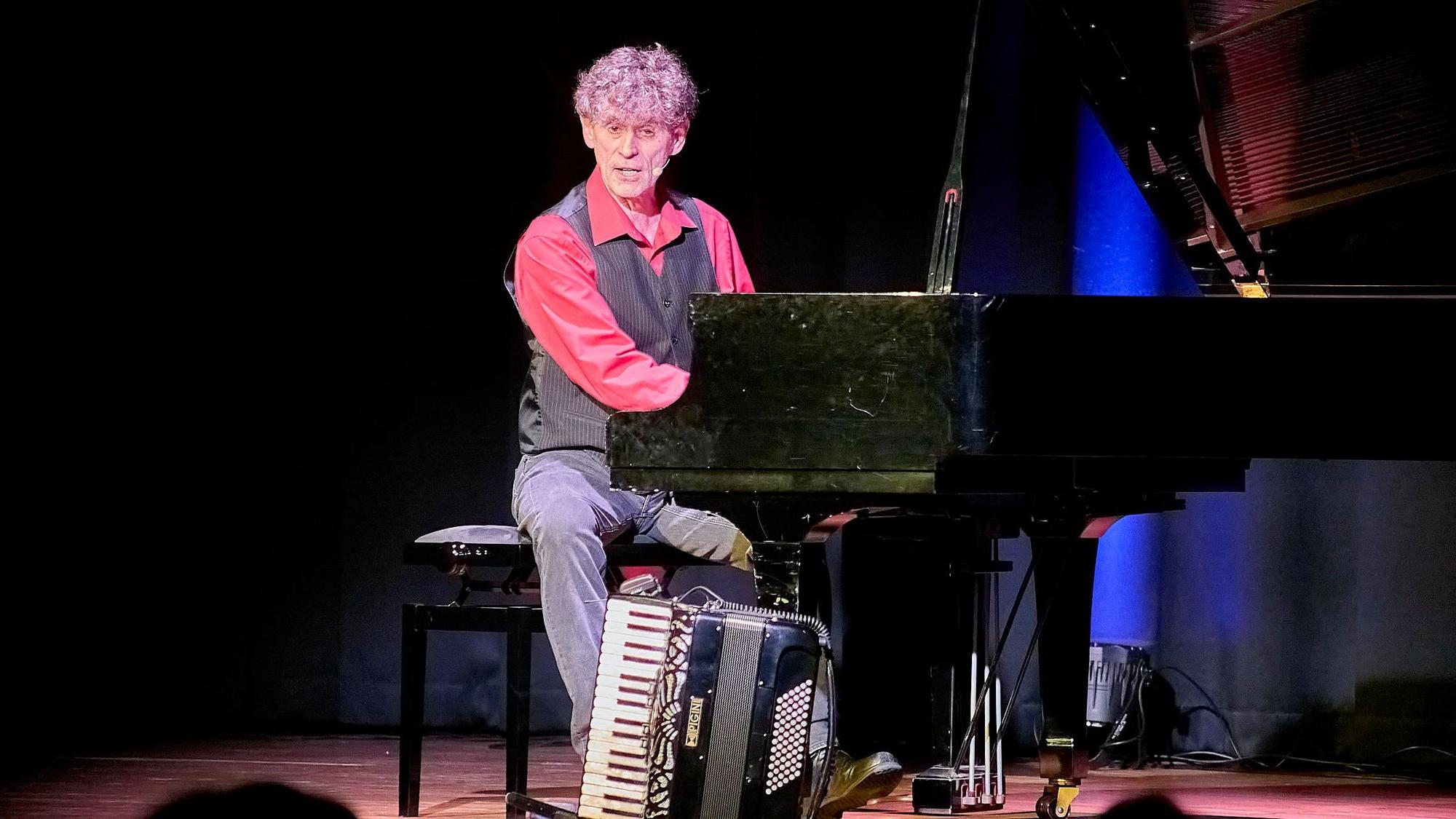 Axel Pätz sitzt am Flügel, auf dem Boden steht ein Akkordeon.