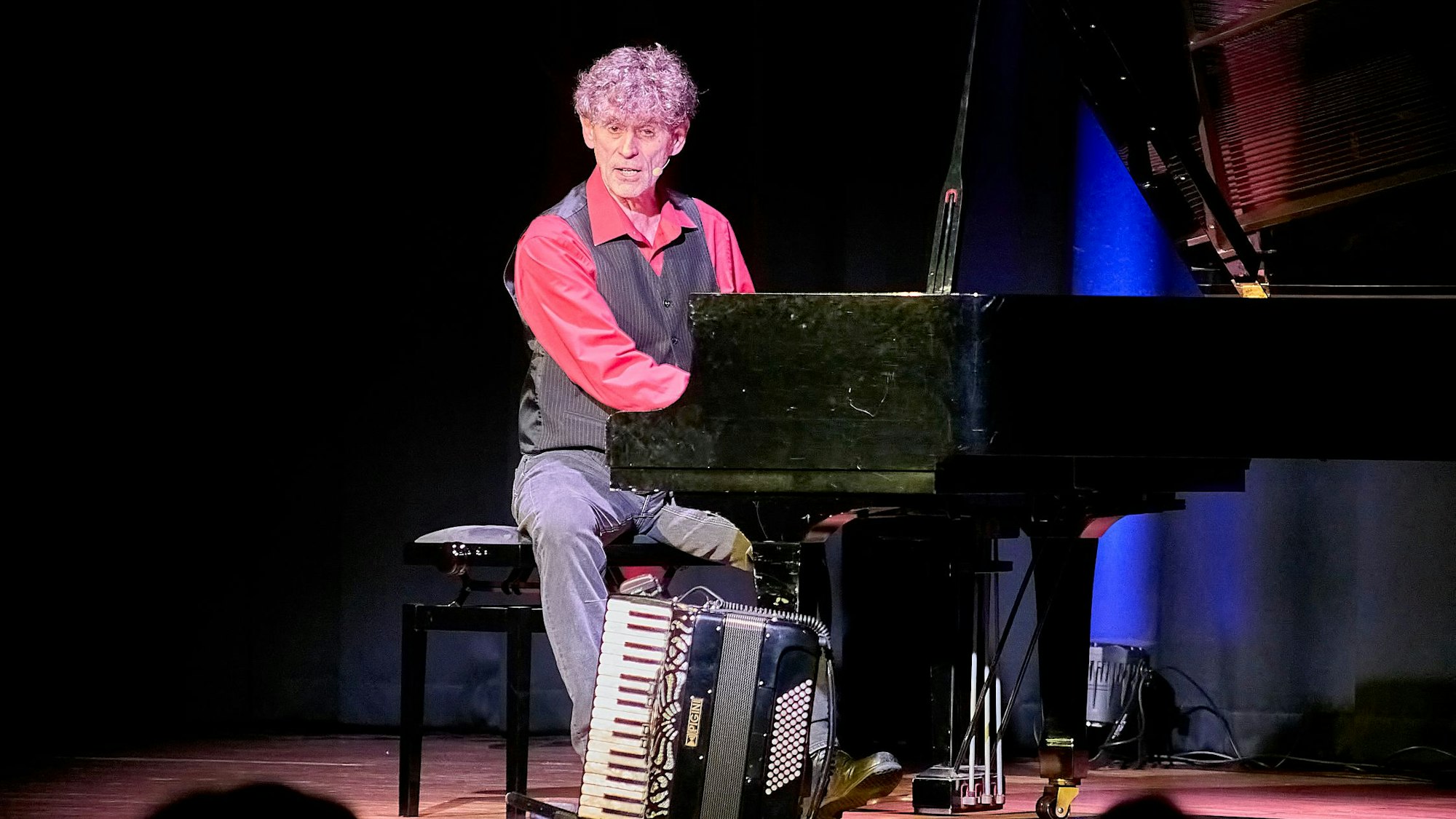 Axel Pätz sitzt am Flügel, auf dem Boden steht ein Akkordeon.