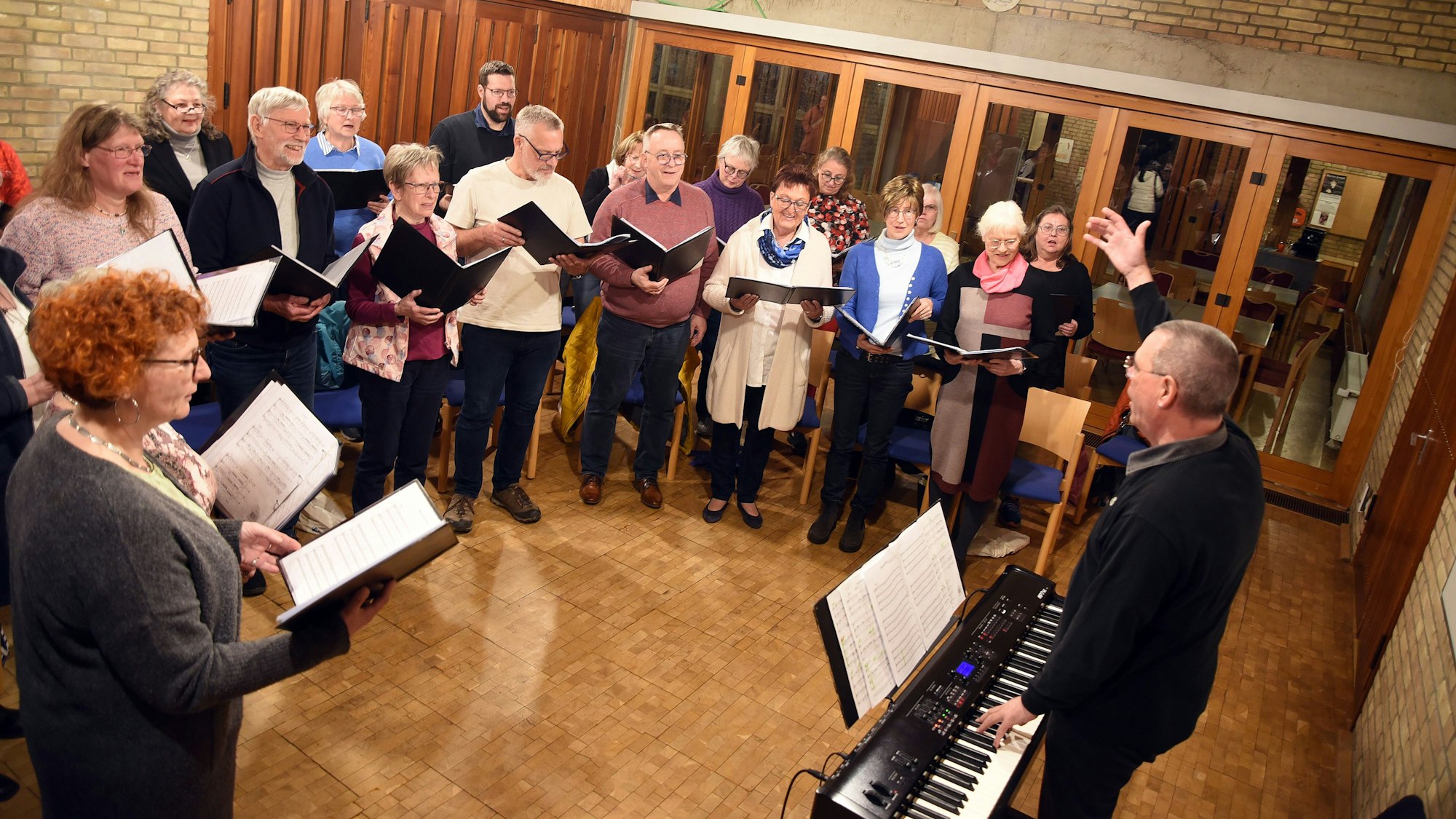 Sängerinnen und Sänger stehen im Halbkreis um einen Chorleiter.