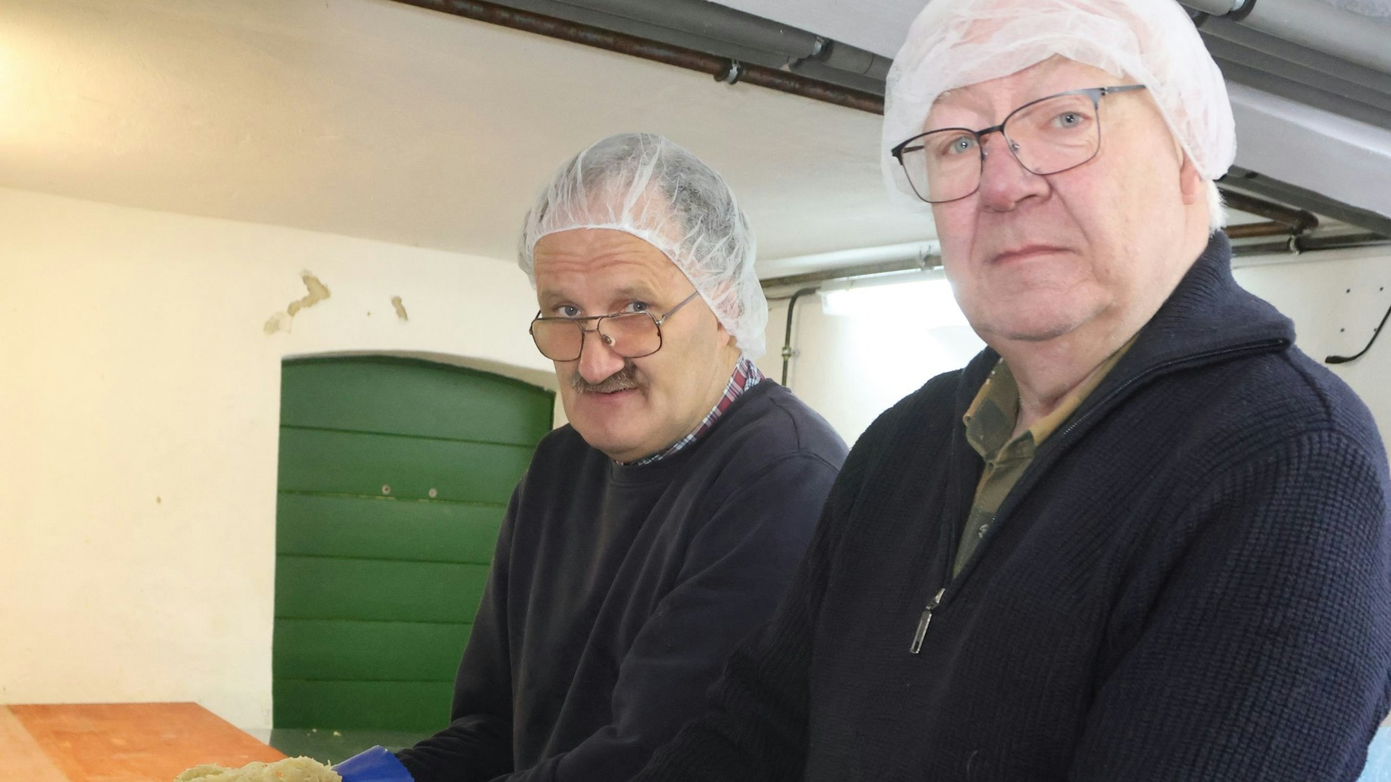 Zwei Männer an einem Fass mit Sauerkraut.