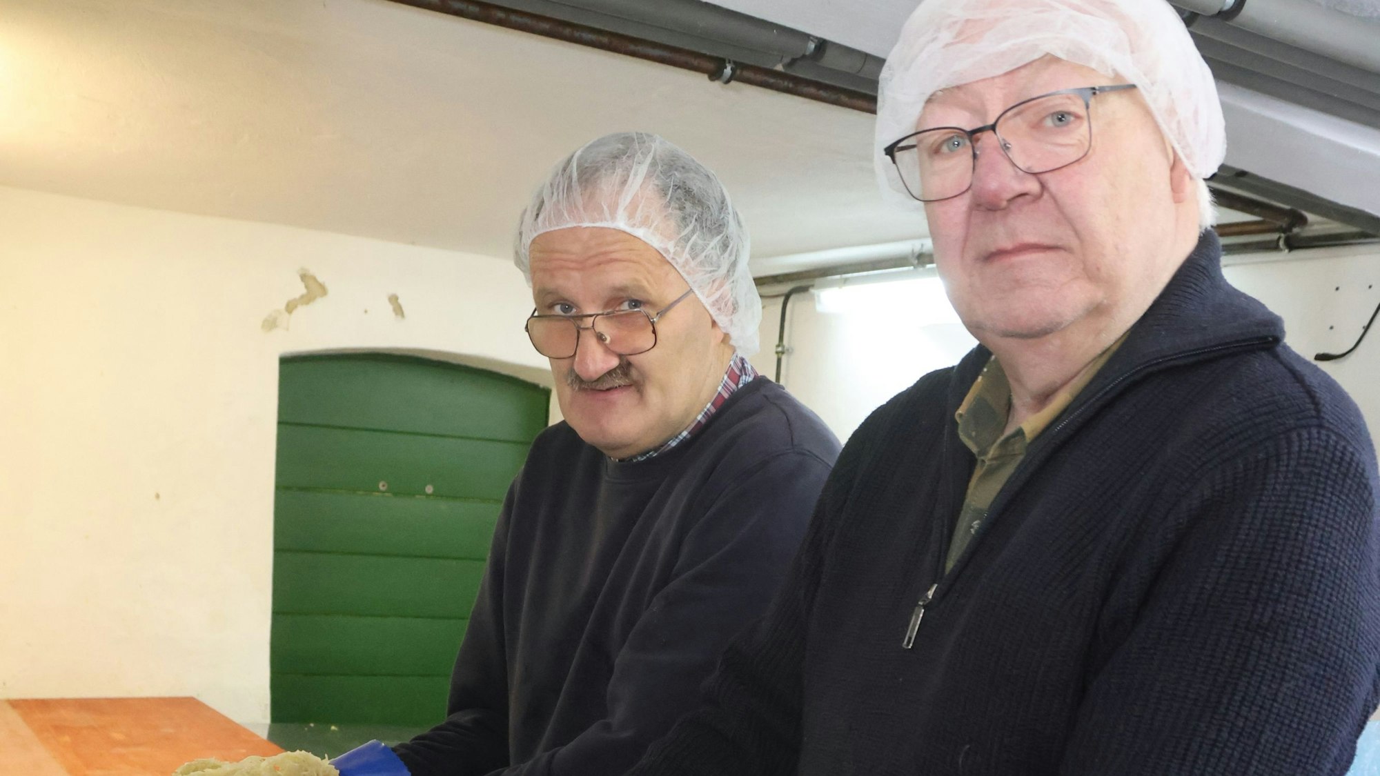 Zwei Männer an einem Fass mit Sauerkraut.