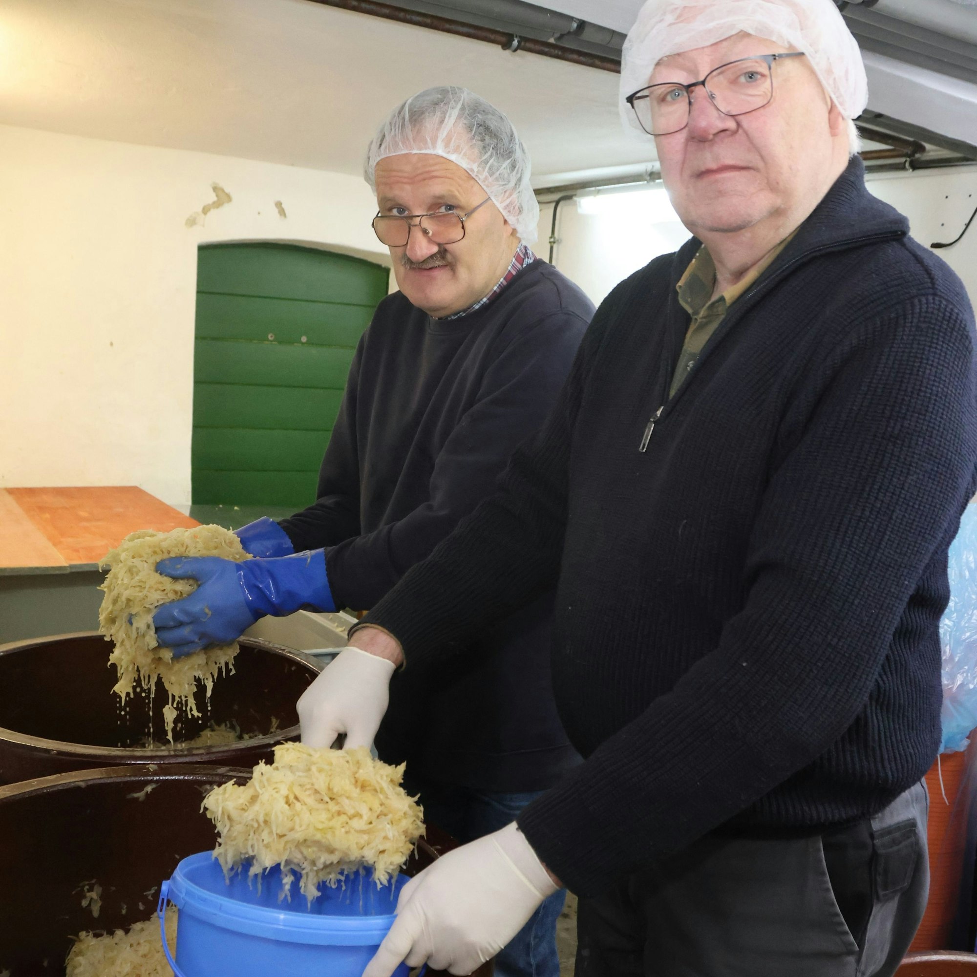 Zwei Männer an einem Fass mit Sauerkraut.