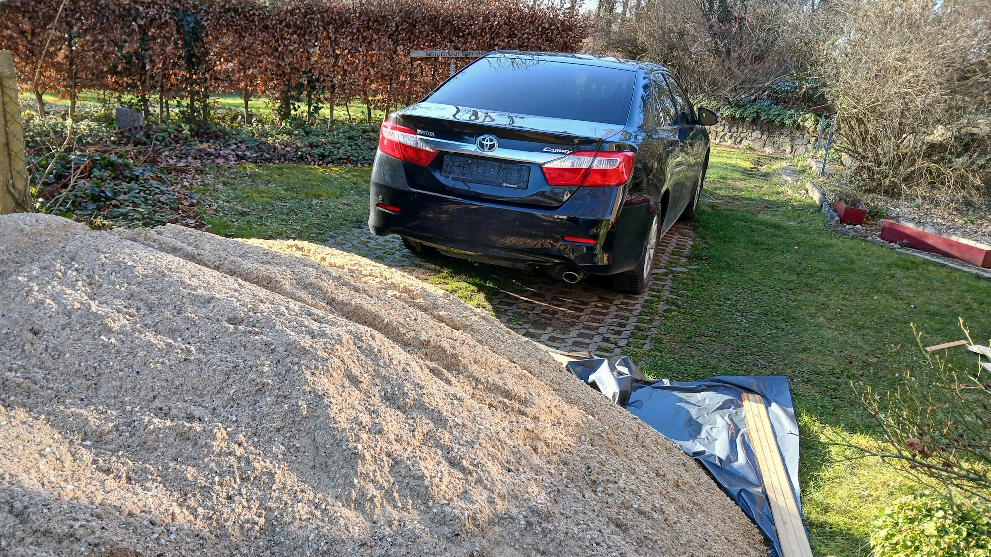 Ein schwarzer Toyota ohne Nummernschilder steht auf einem Parkplatz hinter einem Sandhaufen.
