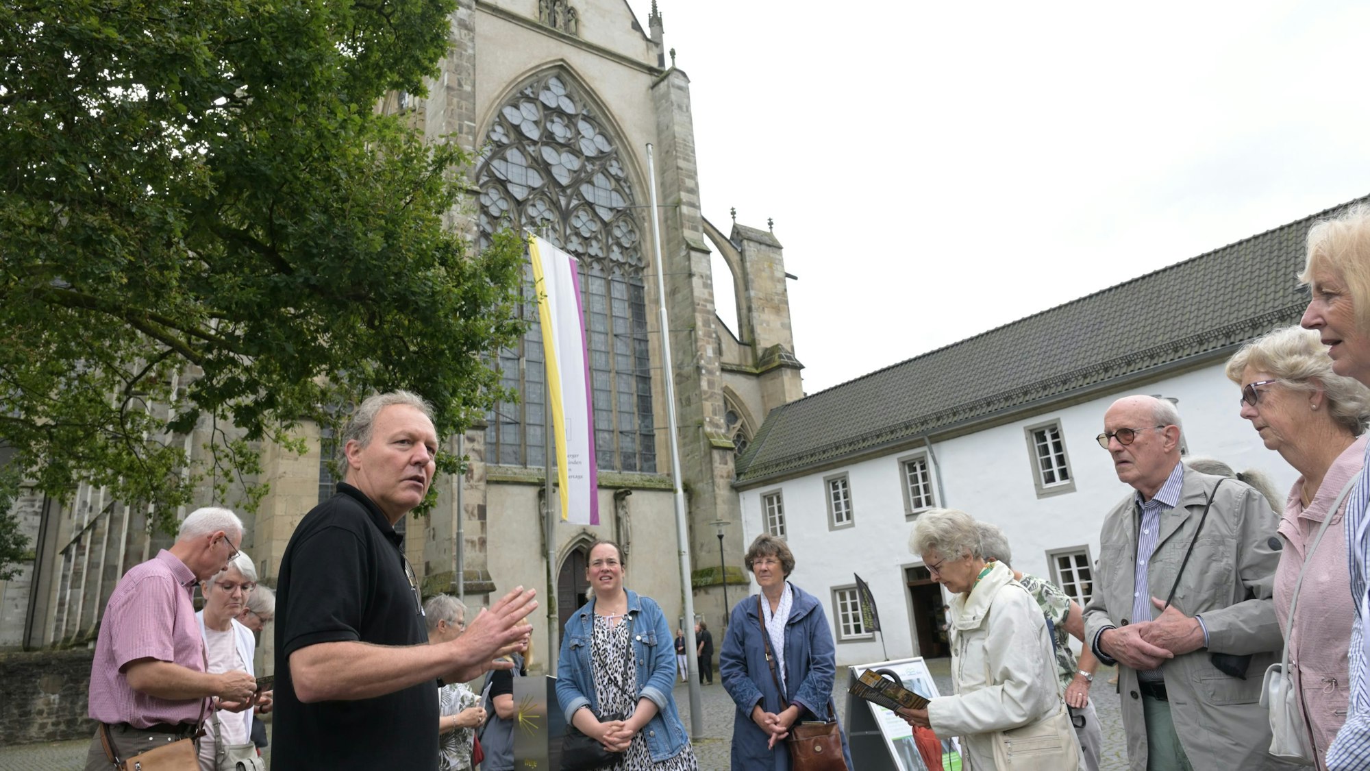 Eine Besuchergruppe steht vor dem Westportal des Altenberger Doms.