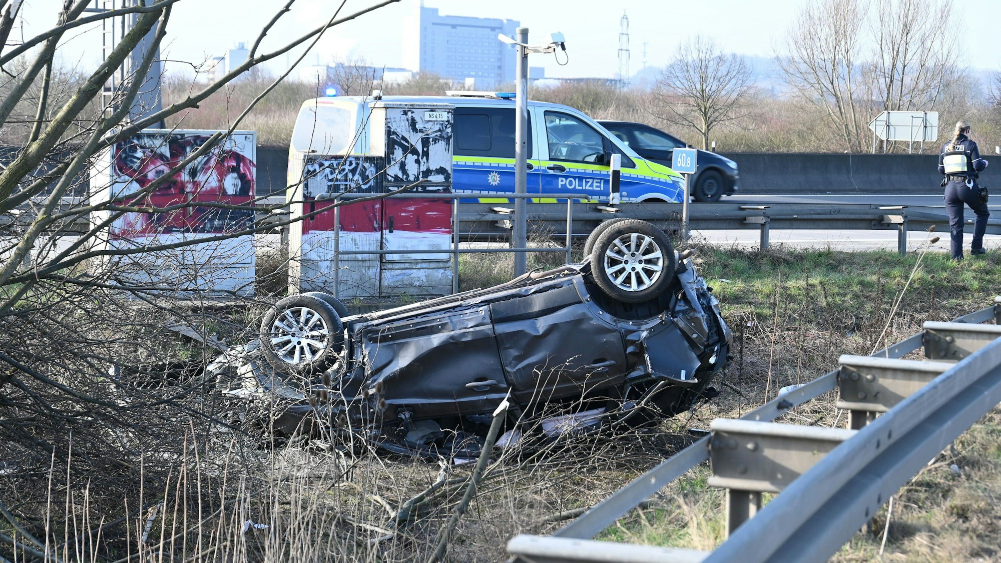 Der Unfallwagen liegt auf dem Dach. Im Hintergrund ist ein Polizeiwagen zu sehen.