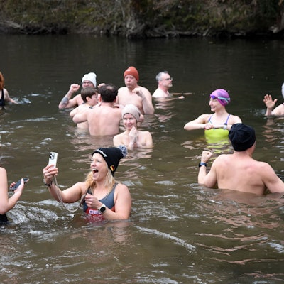 Eine Gruppe Schwimmer beim Eisbaden in der Agger. Eine Frau macht ein Selfie von sich.