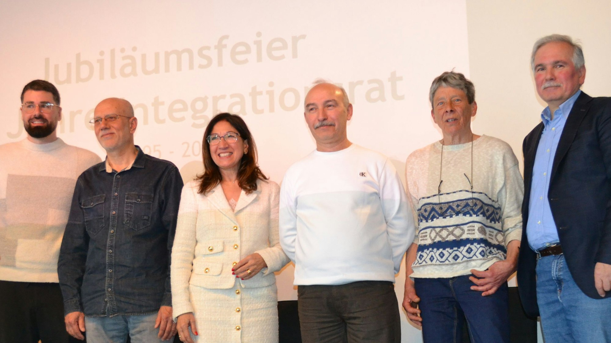 Zu sehen sind der städtische Integrationsbeauftragte Gerrit Scott-Vogelgesang, die Vorsitzende des Integrationsrates Giovanna Keilhau sowie Pioniere des Wesselinger Integrationsrates, die auf einer Bühne stehen.