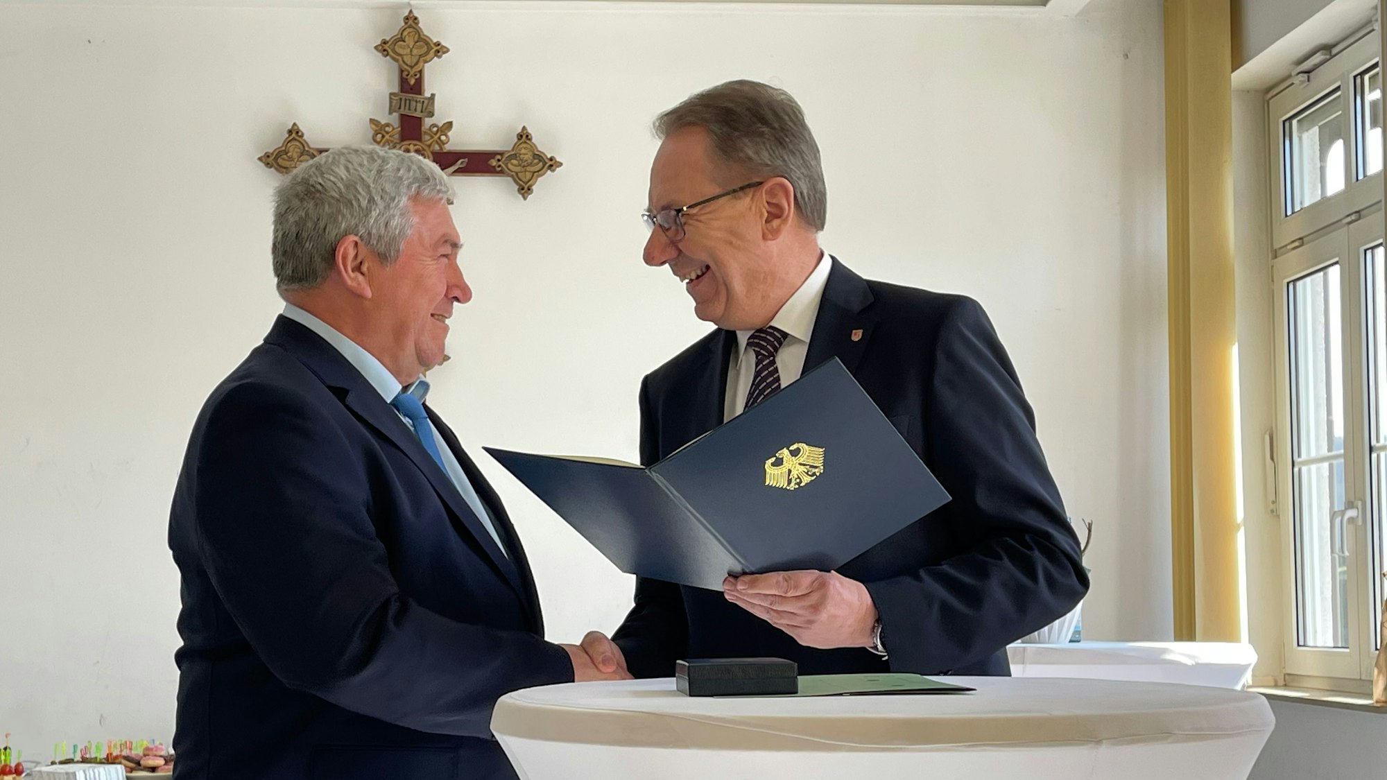 Landrat Jochen Hagt gratuliert per Handschlag Hans Schmitz und überreicht ihm einen Verdienstorden.