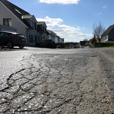 Eine schadhafte Asphaltdecke einer Straße.