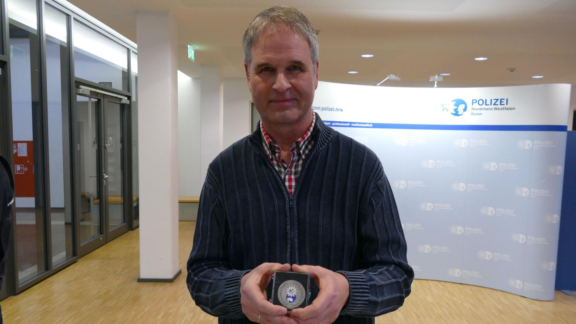 Reinhard van Helden zeigt seine Medaille, die er erhielt, weil er einen Taschendiebstahl verhinderte.