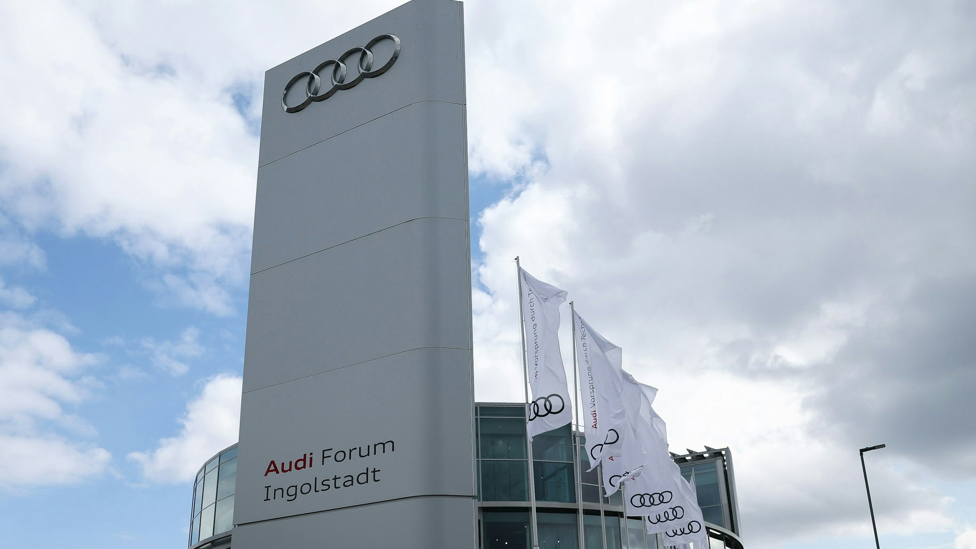Dunkle Wolken sind hinter Fahnen mit dem Logo von Audi vor dem Audi-Forum zu sehen.