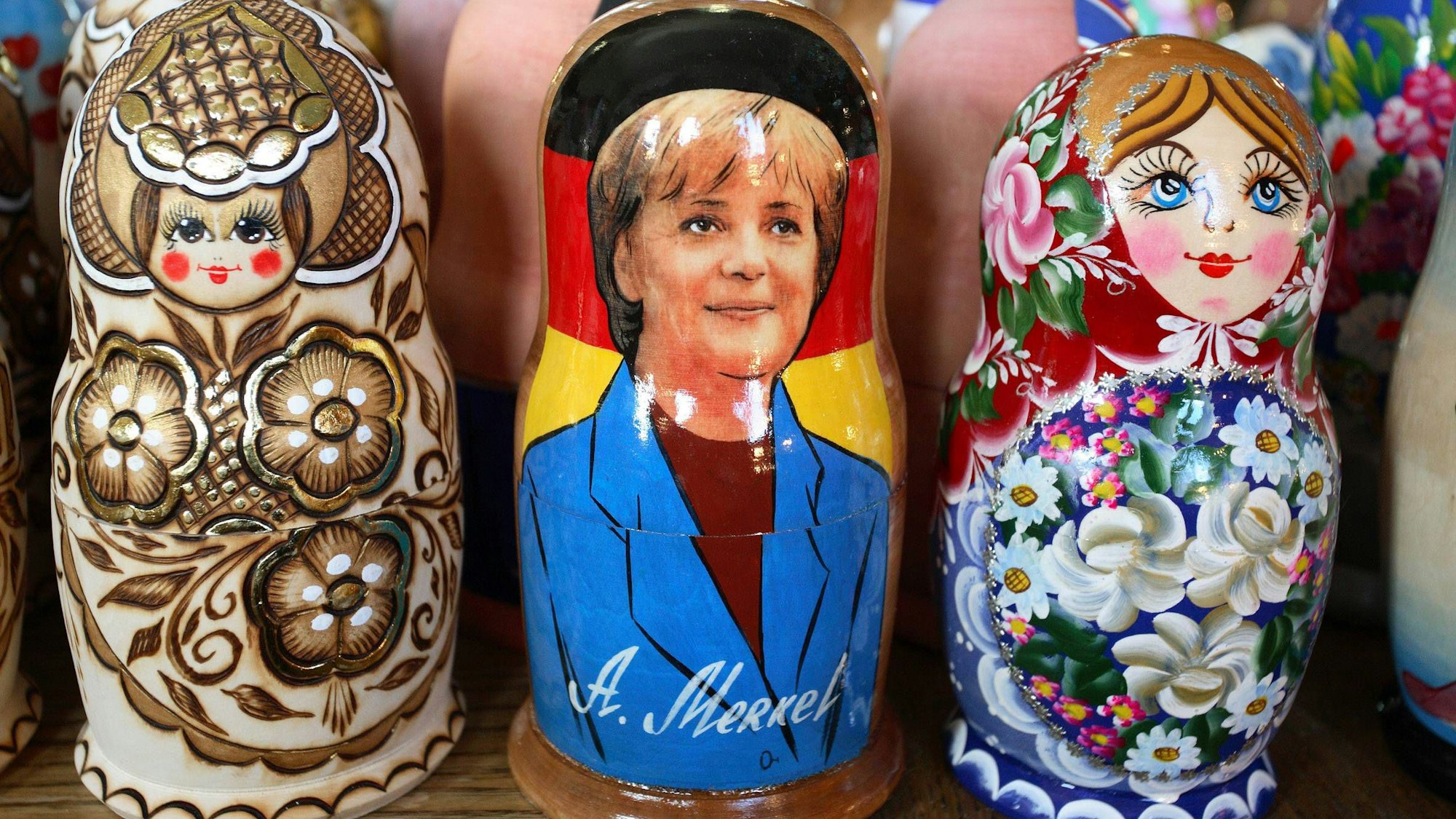 Drei russische Holzpuppen, die mittlere zeigt Altkanzlerin Merkel