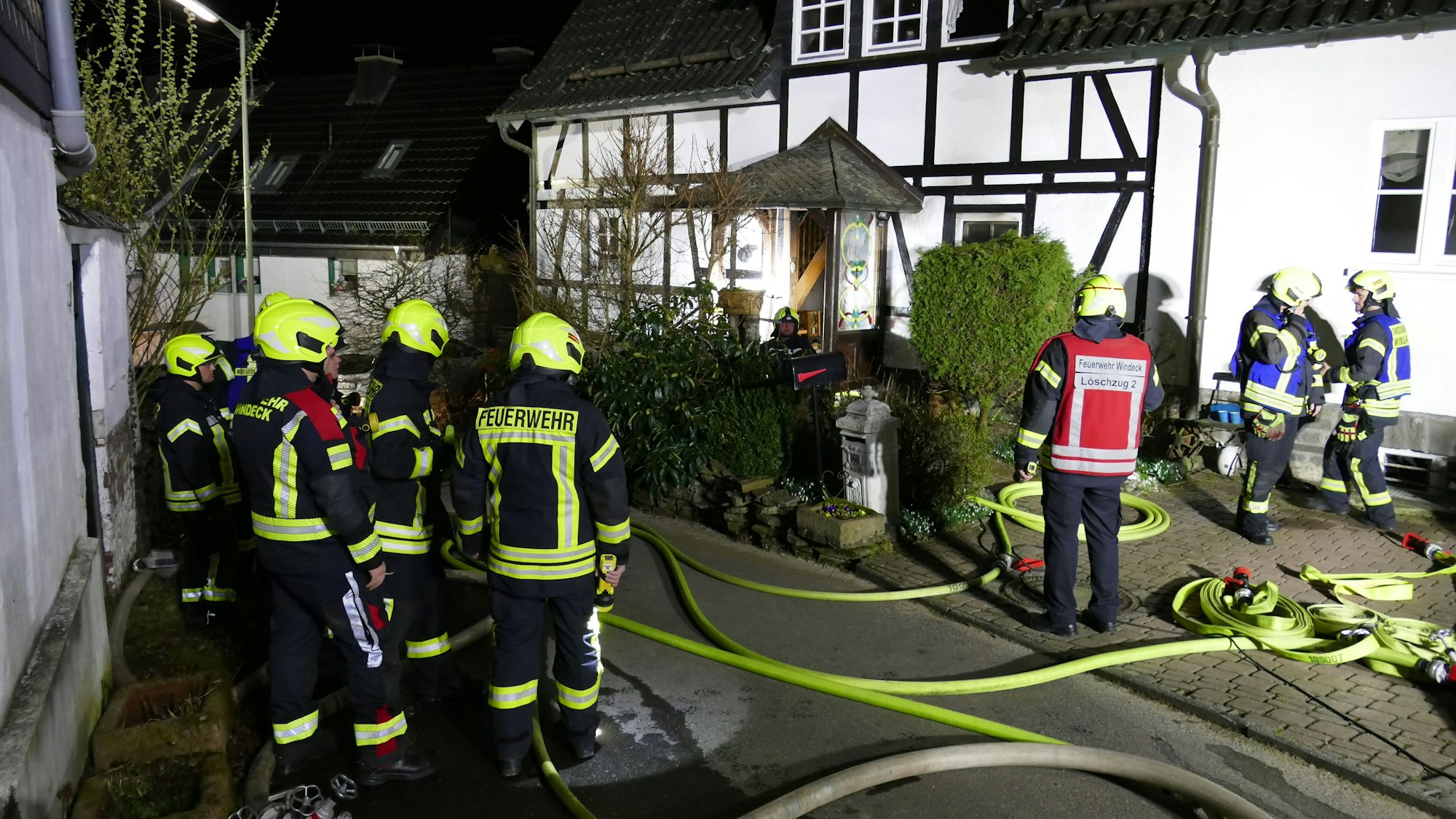 Feuerwehrleute stehen vor einem Fachwerkhaus.