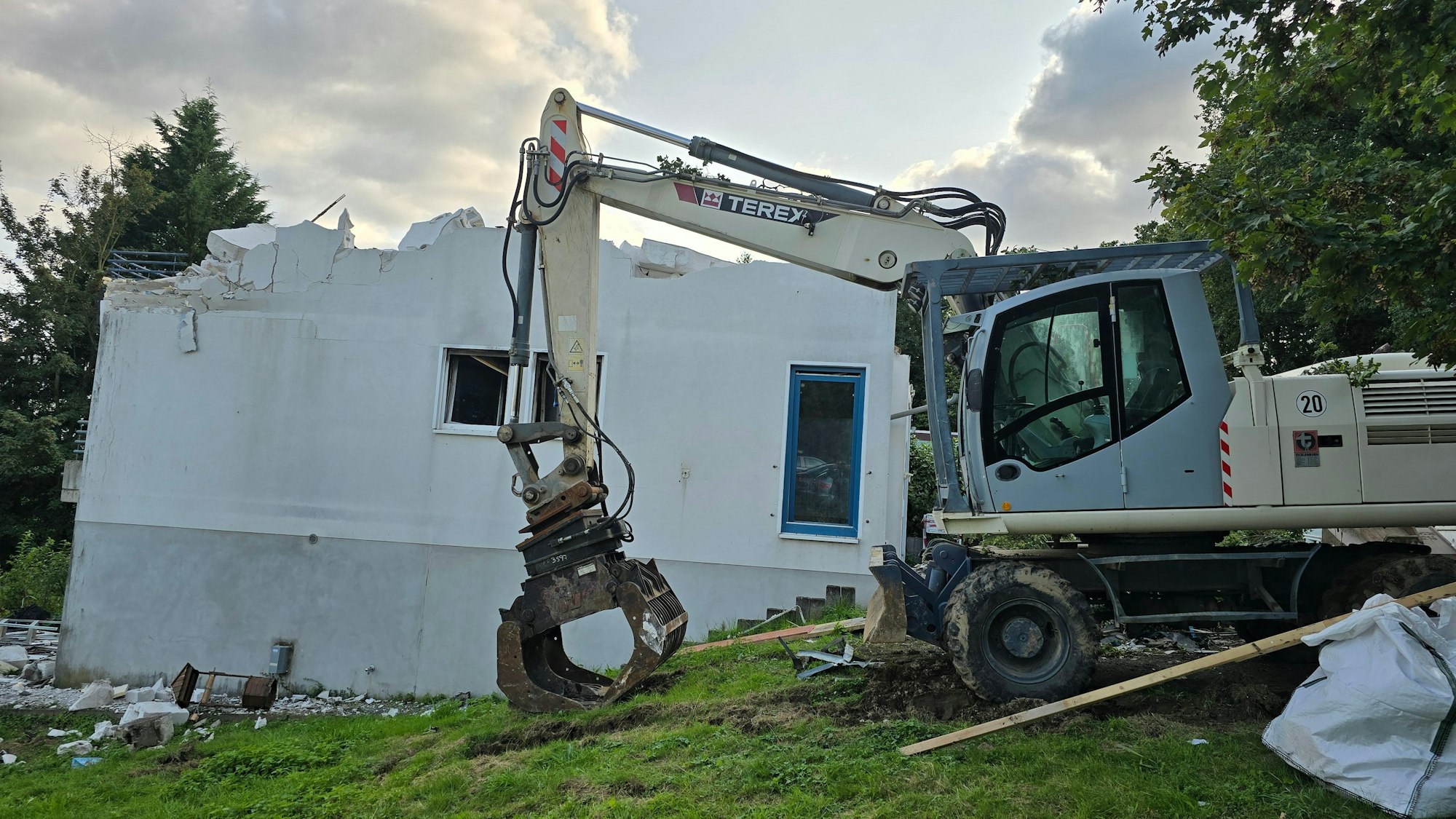 Das Foto zeigt einen Bagger bei den Abrissarbeiten, der Dachstuhl des Hauses fehlt.