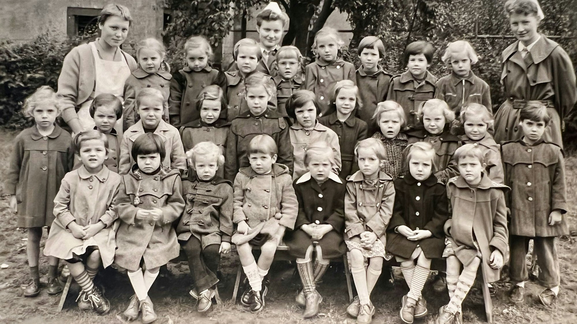 Auf dem SW-Bild ist eine Gruppe von Kindern mit Pflegerinnen zu sehen.